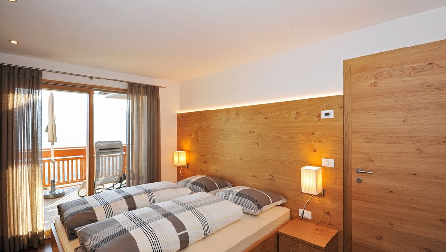 Modernes Schlafzimmer mit Doppelbett, Holzwänden und Balkonblick