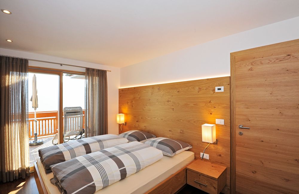 Modernes Schlafzimmer mit Doppelbett, Holzwänden und Balkonblick