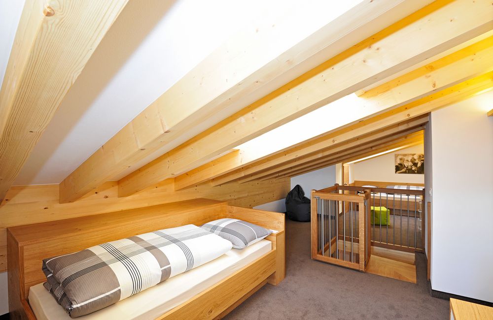 Dachboden mit geneigter Holzdecke, Bett und Treppenschutzgitter