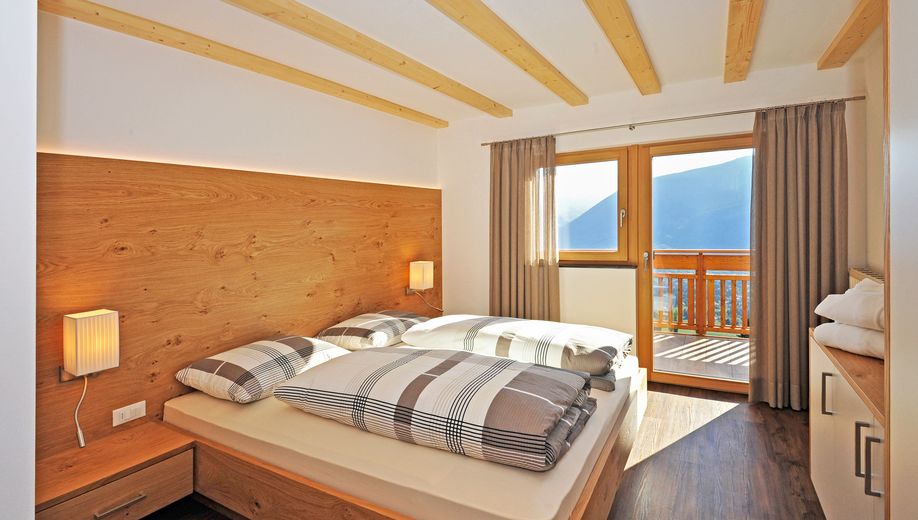 Modernes Schlafzimmer mit Holzbett, Panoramafenster und Bergblick