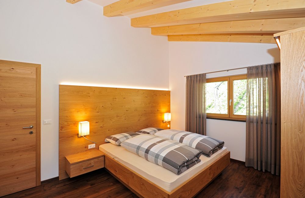 Hell eingerichtetes Schlafzimmer mit Holzmöbeln und großem Fenster.