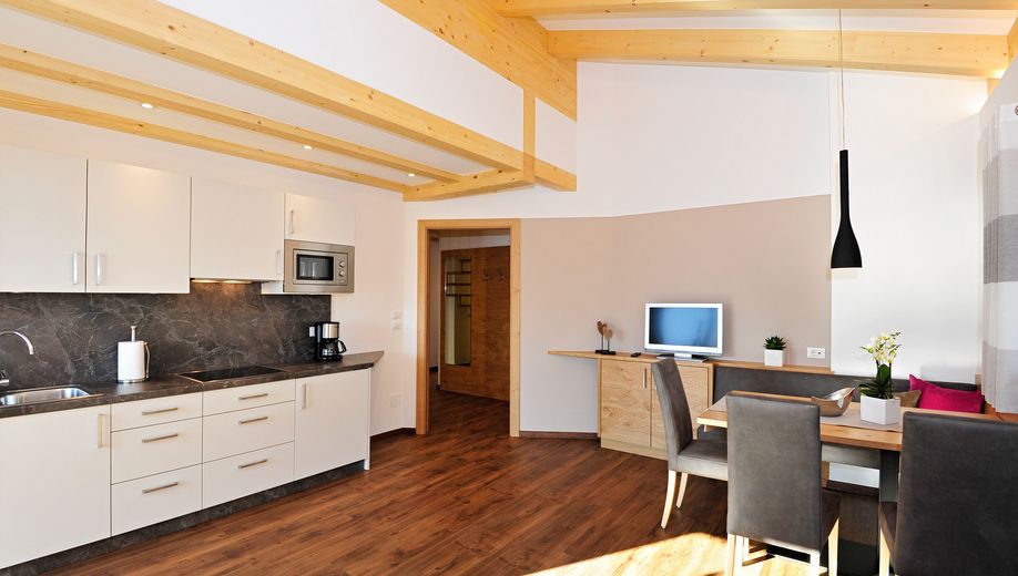 Moderner Wohnküchenbereich mit Holzbalkendecke, Esstisch und Einbauküche.