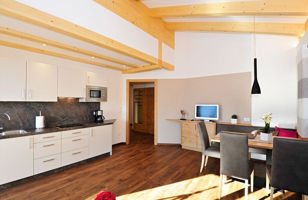 Moderner Wohnküchenbereich mit Holzbalkendecke, Esstisch und Einbauküche.