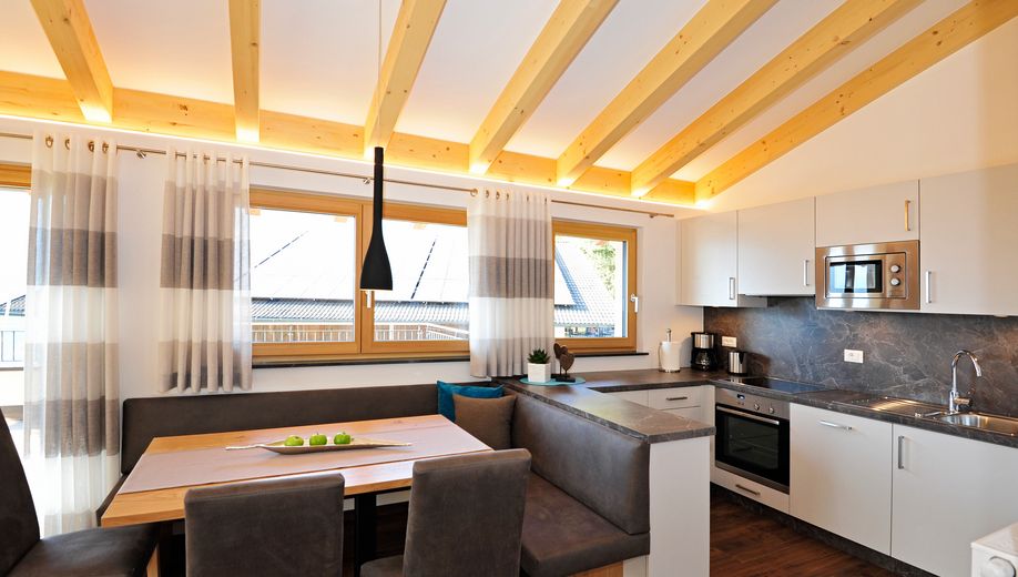 Moderne offene Küche mit Holzdecke, Esstisch und Eckbank