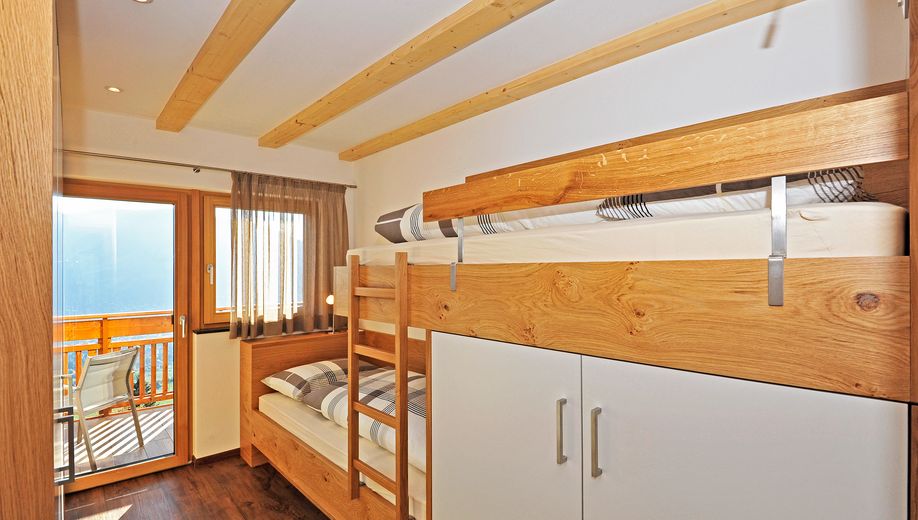 Kleines Schlafzimmer mit Etagenbett aus Holz und Balkon mit Stühlen